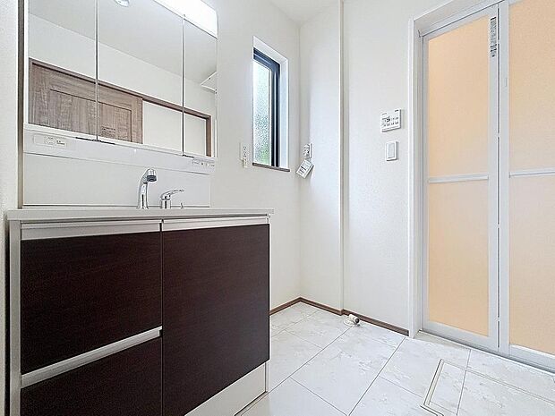 「清潔な印象の洗面室」明るく清潔感のある色調で纏められた洗面室は、機能性に富んだ三面鏡と使い勝手の良い収納を完備した洗面台を設置。洗濯機置場も完備し、大変充実しております。