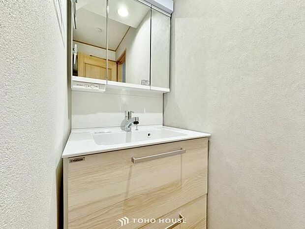 「洗面化粧台」白を基調とした清潔感溢れるデザインの洗面化粧台です。三面鏡の裏側や足元のキャビネットなど、収納豊富で実用的な洗面空間です。