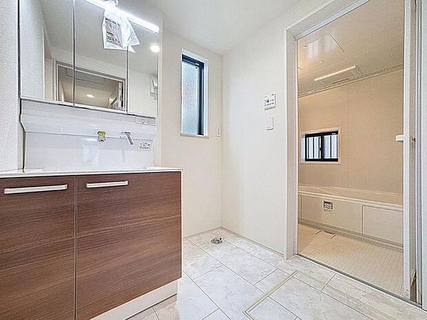 「清潔な印象の洗面室」明るく清潔感のある色調で纏められた洗面室は、機能性に富んだ三面鏡と使い勝手の良い収納を完備した洗面台を設置。洗濯機置場も完備し、大変充実しております。