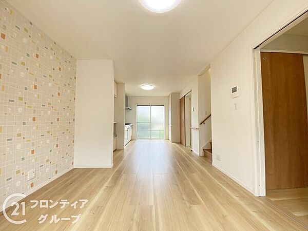 柔らかな色合いのフローリングが心地よい、陽だまりのようなリビングです。アクセントクロスが空間に彩りを添え、洗練された雰囲気を醸し出しています。家族が自然と集まりたくなるような、開放感のある設計ですね