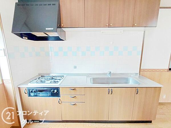 温もりを感じる木目調のパネルを採用した、使い勝手の良いシステムキッチンです。上下にたっぷりと収納スペースを確保しており、調理器具や食器もすっきりと整理整頓することができます