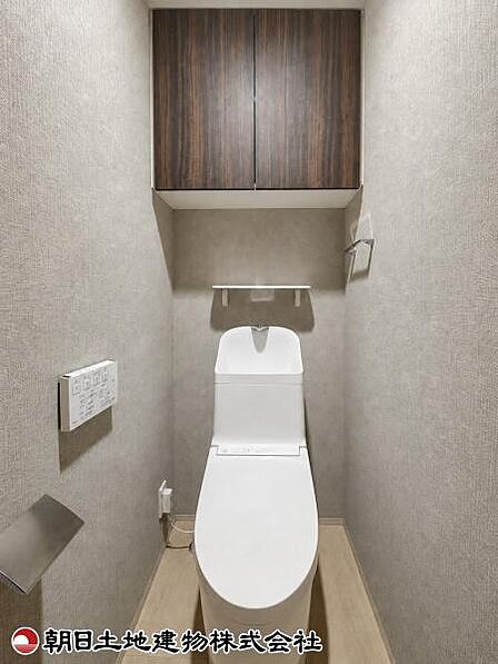 落ち着いた色調で統一された、上部収納付きの清潔感あふれるトイレです。