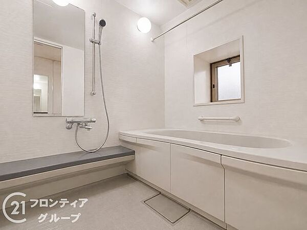 白を基調とした清潔感あふれる浴室です。ゆったりとした浴槽は一日の疲れを癒やすのに最適で、窓があるため開放感も感じられます。手すり付きの安心設計で、家族全員が快適に利用できます