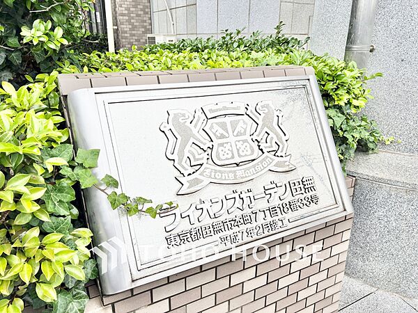 重厚なエンブレムが映える、気品に満ちた館銘板。洗練されたヴィンテージ感と、植栽の鮮やかな緑が調和した美しいエントランスアプローチが、居住者やゲストを心地よく迎え入れます。