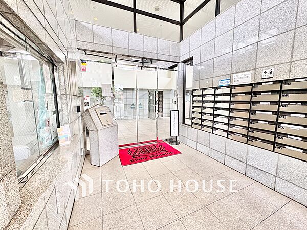 【ライオンズクオリティ】気品と開放感が共存するエントランスホール高い吹き抜け風の天井と、ブランドを象徴する鮮やかな赤いマットが出迎える上質空間。防犯カメラも作動中で、毎日の暮らしを優しく見守ります