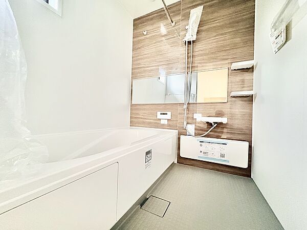 【癒しのバスタイム】木目調のパネルが温かみを演出。ワイドミラーが空間を広く見せます。小窓付きで換気もしやすく、ご家族でゆったりと一日の疲れを癒せるリラックス空間です。