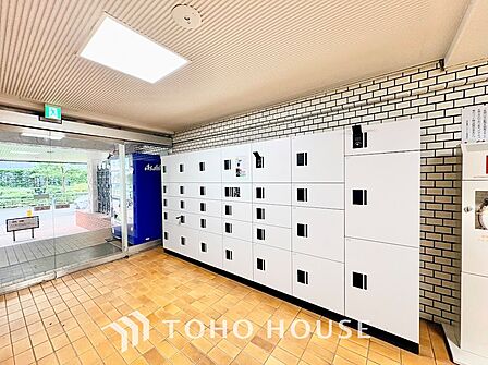 居住者のプライバシーを守る奥まった設計の郵便受けスペース。ステンレス製のダイヤル錠付きポストが整然と配置され、明るい照明と広い通路で日々心地よく手紙や書類を確認できます。