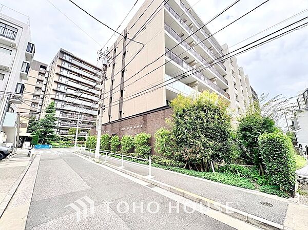 美しく剪定された生垣が敷地沿いに続き、プライバシーと歩行者の安全に配慮された開放的な接道環境。シックなネイビー調タイルが高級感を漂わせ、街並みと調和するモダンな佇まいです。