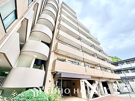 美しく剪定された生垣が敷地沿いに続き、プライバシーと歩行者の安全に配慮された開放的な接道環境。シックなネイビー調タイルが高級感を漂わせ、街並みと調和するモダンな佇まいです。