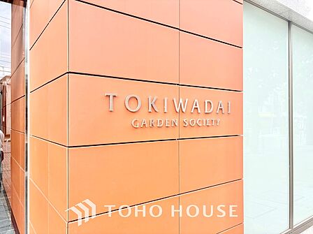 凹凸感が重厚な割り肌調タイルに掲げられた「シティテラス板橋蓮根」のステンレス切り文字サイン。青々とした植栽に映える格調高いエンブレムが、住まい手のステータスと所有欲を満たします。