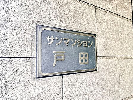 質感の高い御影石調の石張り壁面に美しく配置された「サンマンション戸田」の館銘板。落ち着きと品格を感じさせるデザインが、歴史と安定感のある住まいの風格を優しく象徴しています。
