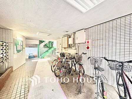 大切な愛車を雨風から守る、安心の屋根付き(屋内型)駐輪スペース。共用部には掲示板や防犯・防災設備が整っており、日頃の管理体制の良さが伺えます。