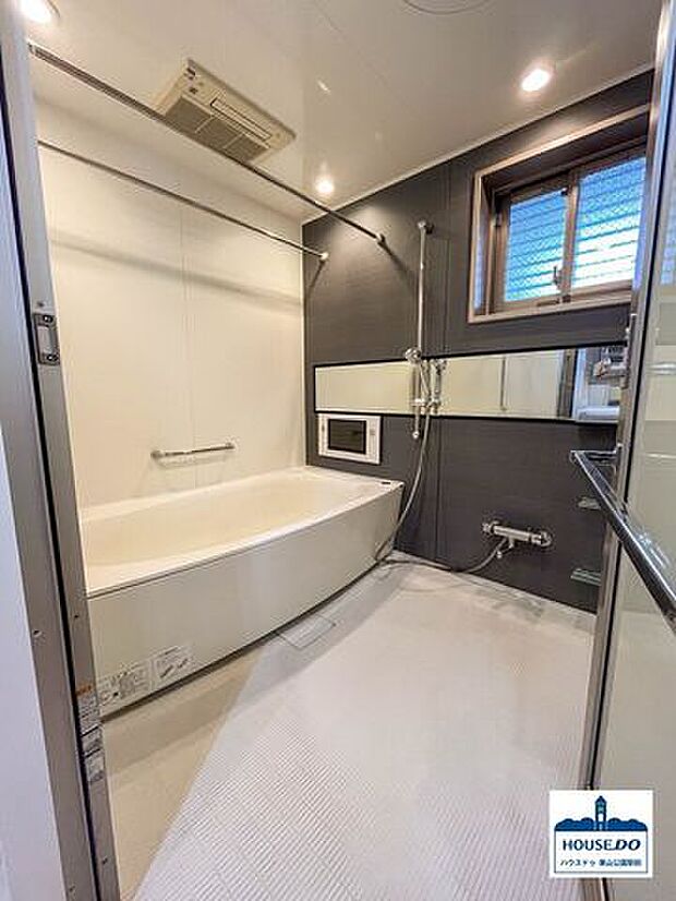 シンプルで落ち着きのある内装の窓付き浴室。浴室鏡が横向きに設置されて室内の広さをより感じ取りやすくなっています