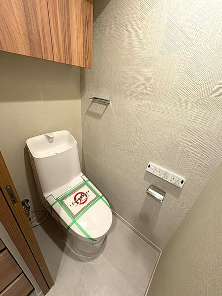 ウォシュレット機能付きのトイレになります。タンク上部には吊戸棚が設置されています。