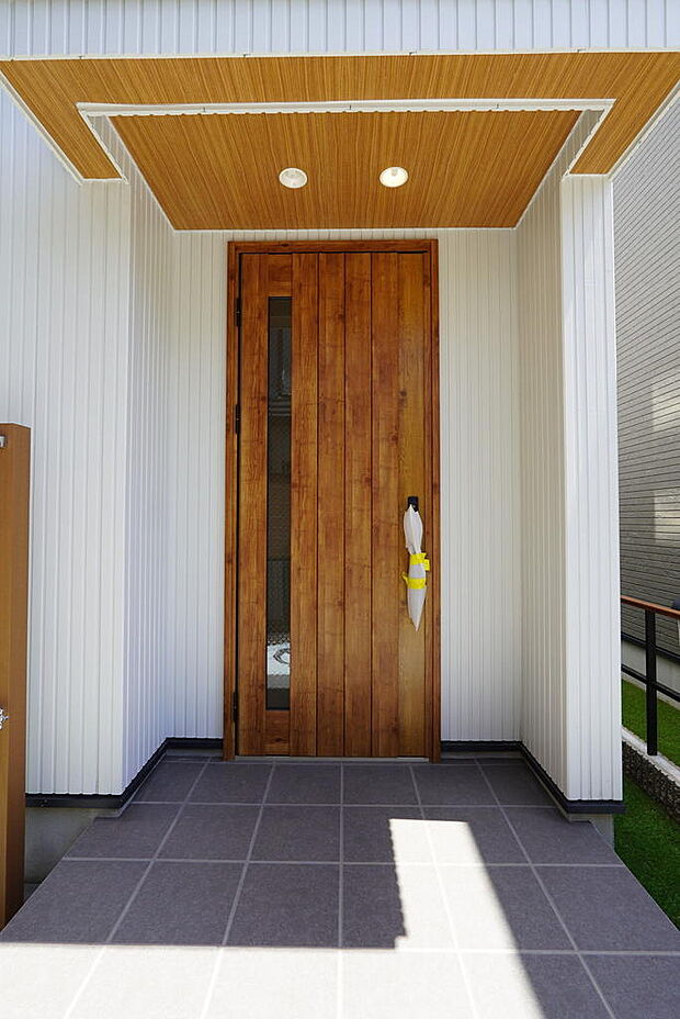 重厚感のある木目調の玄関ドア。明かり取りも設けられ、日中は照明いらずの玄関ホールです