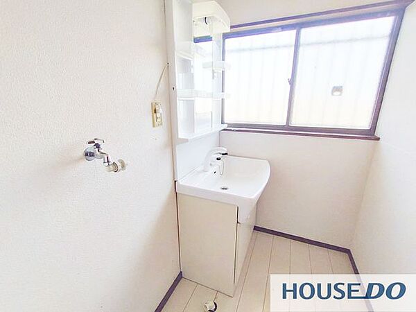 窓のある明るい洗面所。鏡付きの洗面化粧台を備え、使いやすい配置です。
