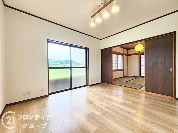 木目調のフローリングが心地よいリビング。隣接する和室の戸を開ければ、さらに開放的な大空間が広がります。窓から差し込む柔らかな光と、外の緑に癒やされる穏やかな時間が流れる空間です