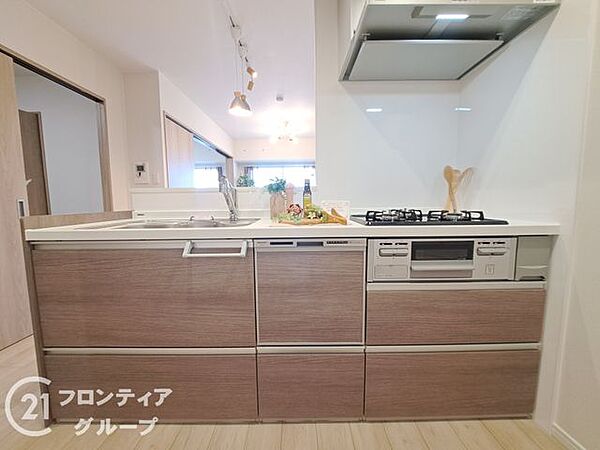 木目調のパネルが温かみを添える、上質で機能的なシステムキッチンです。リビングを見渡せる開放的な設計により、家族との会話を楽しみながら快適にお料理ができる贅沢な空間に仕上がっています