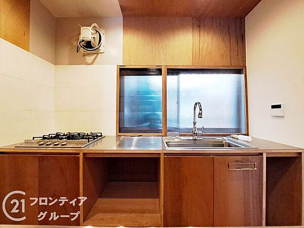 温もりを感じる木目調のキャビネットが印象的なキッチンです。シンクの正面には窓が配置されており、外の景色を眺めながら開放的な気分でお料理を楽しめます。収納スペースも豊富で、作業スペースを広く保てます
