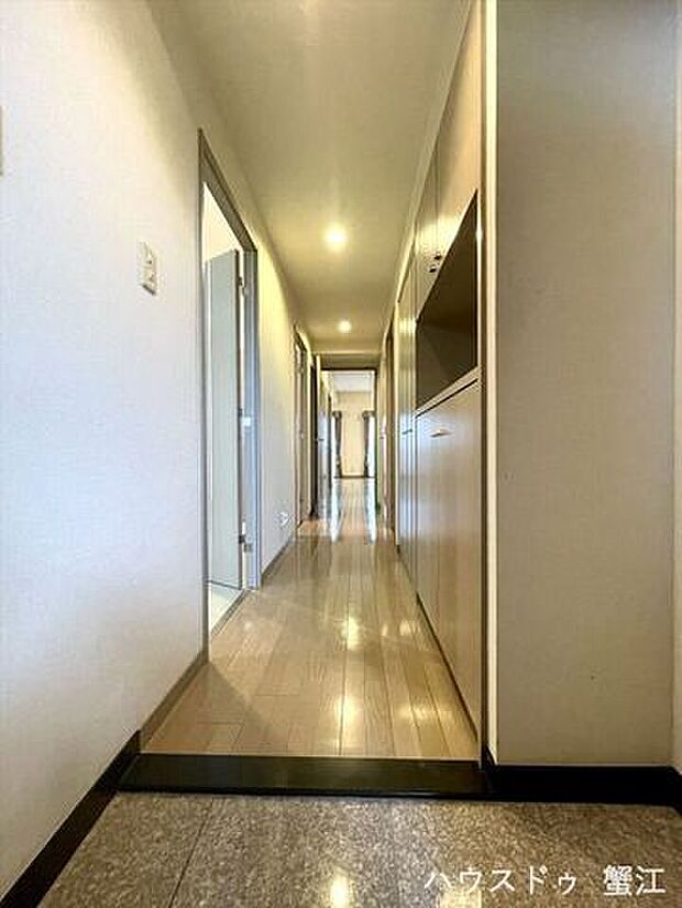 玄関からリビングまで一直線に繋がる廊下。等間隔で設置された灯りが床面に反射して見栄えがします。