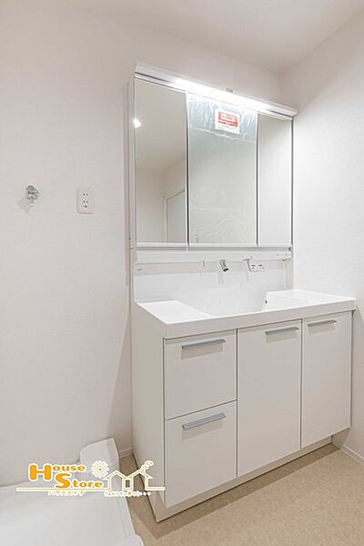 大きな三面鏡付き洗面化粧台を備えた機能的な洗面室。鏡裏収納も活用でき、洗面用品や化粧品類をすっきりと整理整頓していただけます。