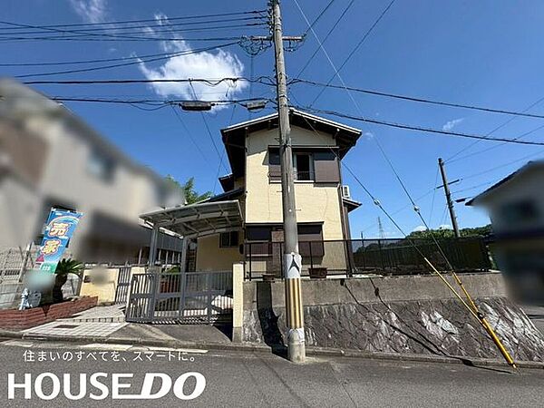 高台に建つ2階建て住宅の外観。石積み調の擁壁と黒基調のフェンスが上品な佇まいです。