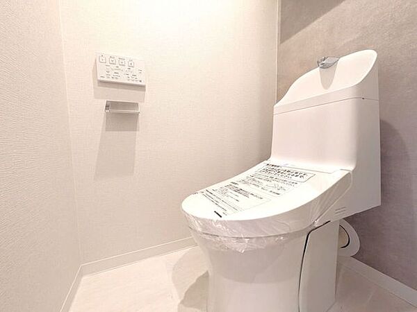 ■温水洗浄便座付きトイレ■白を基調とした内装に、おしゃれなアクセントクロスが映える落ち着いた空間です。上部にはトイレットペーパーなどのストックをスッキリ隠して収納できる、扉付きの棚を備えています。