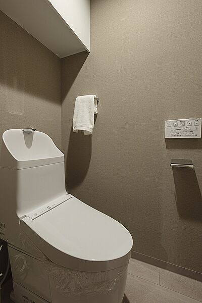 【トイレ】毎日清潔に使用できる温水洗浄便座付き。壁にリモコンを設置しているので、操作がしやすいです。トイレットペーパーなどの保管に便利な吊戸棚あり。