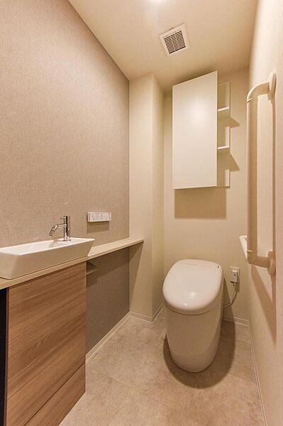【トイレ】カウンターと手洗い器付きの、ゆとりある広さのトイレです。吊戸棚には、トイレットペーパーや衛生用品などをまとめて収納できます。