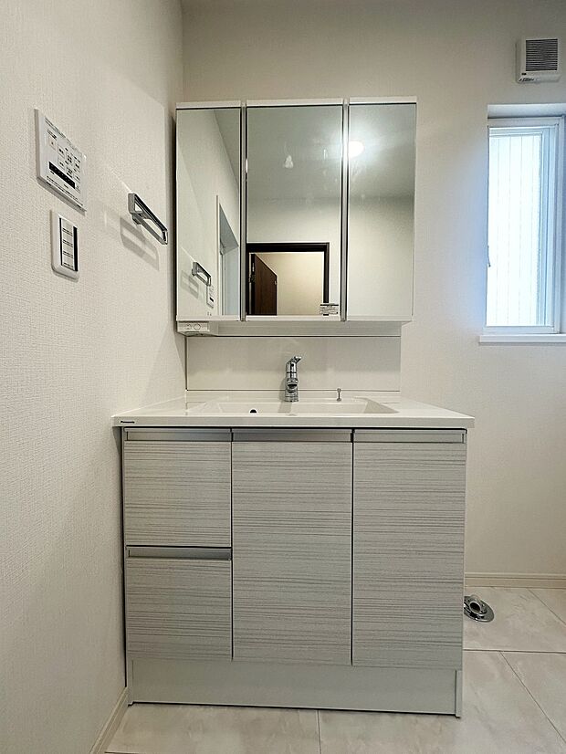 白を基調とし、清潔感のある洗面スペース。洗面台は三面鏡タイプなので後姿のチェックもできて便利です。