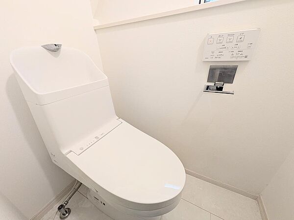 温水洗浄便座を備えた快適なトイレ。操作パネルは壁付けで、空間をすっきりと保てる設計です。