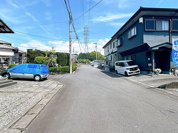 前面道路含む外観写真。幅の広い平坦な舗装公道に面し、車の出し入れもしやすい静かな住宅地です。