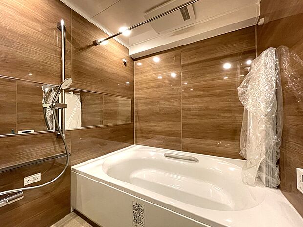 光沢感のあるウッド調パネルの落ち着いた内装です。1618サイズの大型バスルームで、ゆったりとしたリラックス空間となっています。浴室換気乾燥機付きで、バスタイムも快適です。
