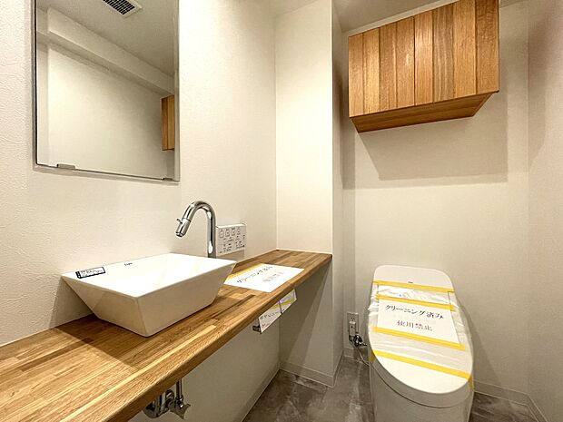 タンクレスですっきりとしたデザインのウォシュレット付きトイレです。吊戸棚も設置されており、トイレットペーパーなどの消耗品の収納ができます。便利な専用手洗いスペースも付いています。
