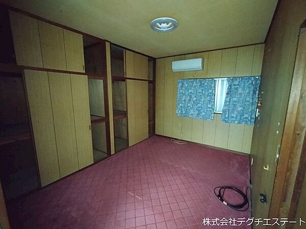 壁面収納を備えた、落ち着きのあるじゅうたん敷きの居室。