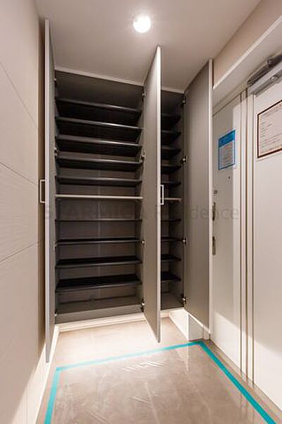 大容量の下足収納を備え、足元から明るい照明が照らす玄関
