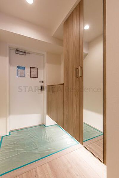 大容量の下足収納を備え、足元から明るい照明が照らす玄関
