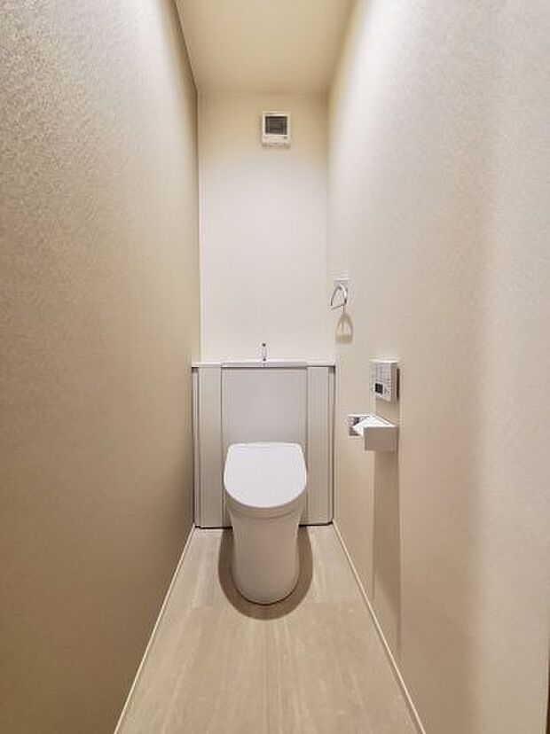 温水洗浄機能の付いたタンクレスのトイレです。手洗い器とトイレ用品が収納できる棚が一体となっており、すっきりとしたトイレ空間になっています。換気扇もついています。