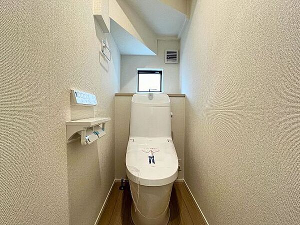 白を基調としたシンプルな壁紙のトイレです。小窓の手前には芳香剤を置いたり小物を置くことができますね。