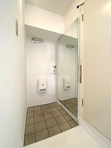 壁面に大型の一面鏡が設置された開放的な玄関スペースです。お出かけ前の身だしなみチェックに大変便利で、床面には品のあるタイルが敷き詰められ清潔感とゆとりを持ってお出迎えできる空間です。