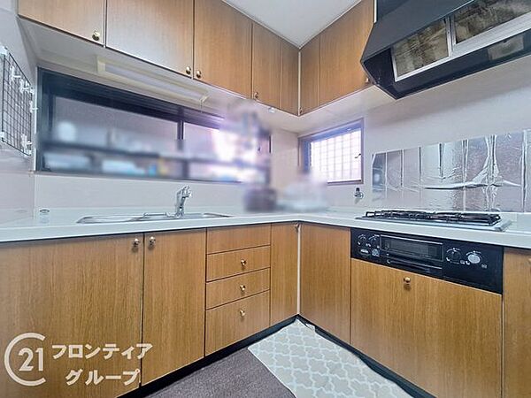 木目調のパネルが温かみを添える、収納力豊富なシステムキッチンです。作業スペースを広く確保できるL型レイアウトを採用しており、ご家族で並んでお料理を楽しむこともできるゆとりある設計になっています