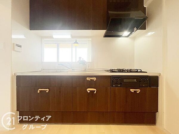洗練されたダークトーンの木目調パネルが、上質な空間を演出するキッチンです。広々としたワークトップは使い勝手も良く、日々の料理時間をより優雅で贅沢なひとときに変えてくれる機能美あふれる設計となっています
