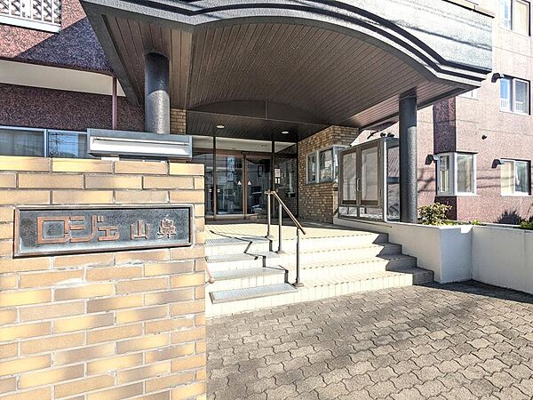 【エントランス】重厚感と温かみを兼ね備えたアプローチデザインが魅力的。毎日の出入りが心地よく、住まう人の誇りを満たす顔となります。周辺環境にも馴染む落ち着いた佇まいで、住まいの安心感を演出します。