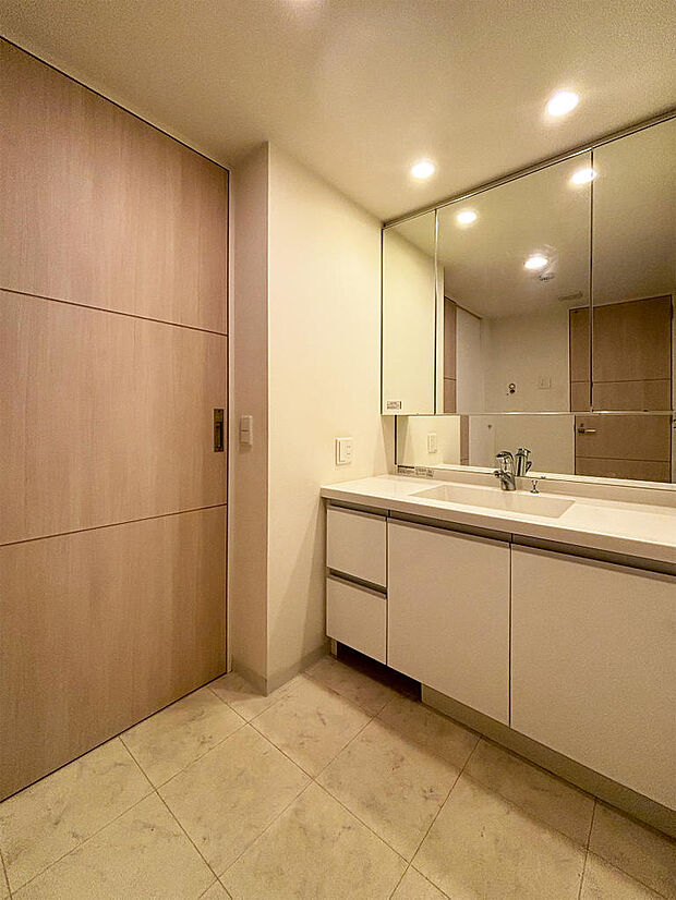 大きな三面鏡収納き洗面化粧台。洗面へのアクセスは家事動線を配慮した2WAYタイプでキッチンと廊下から出入りができます。キッチンと繋がっているのは便利ですよね。