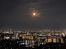 バルコニー：【住戸からの夜景】高層階から望む夜景。街の灯りが遠くまで連なり、空にはやわらかな月明かりが浮かびます。