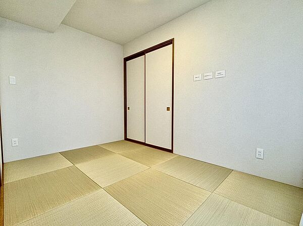 琉球風の縁なし畳がモダンな印象を与える和室には、布団や季節物の収納に便利な大容量の押入れ（またはクローゼット）が備わっており、すっきりとした空間を保てます。
