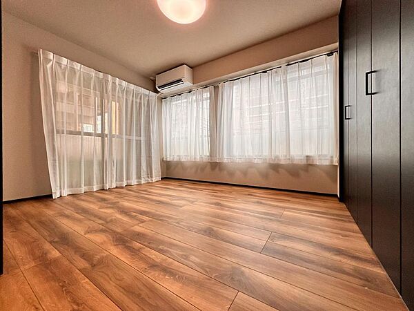 大きな窓からたっぷりと陽光が注がれる明るい空間。一日の疲れをいやしてくれる主寝室。時を忘れて過ごす場所として過ごせるお部屋。木目のフローリングが暖かみのある空間に演出します。