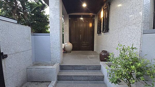 御影石張りの玄関アプローチに重厚感ある無垢材の玄関扉