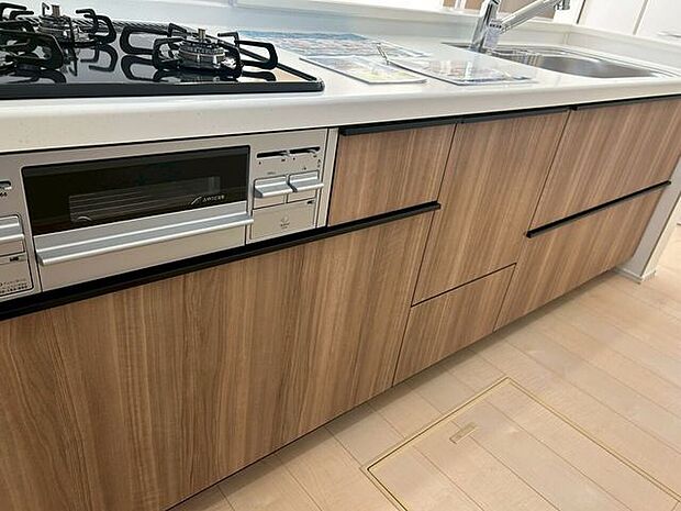 傷や汚れが付きにくい全面エンボス加工シンク。水はねの音や食器が当たる音を大幅に軽減する静音仕様です。キッチンの表面は水はねや汚れからガードするパネルタイプの壁材を採用。