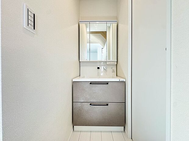 A号棟【洗面台】大きく見やすい三面鏡で清潔感ある洗面台は、身だしなみチェックや肌のお手入れに最適です。何かと物が増える場所だからこそ、スッキリと見映えの良い空間に拵えました。